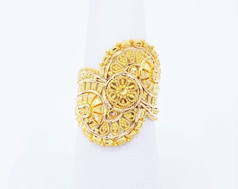May include: A gold ring with a intricate design featuring multiple circular patterns. The ring is made of 22 karat gold and has a unique, ornate style.