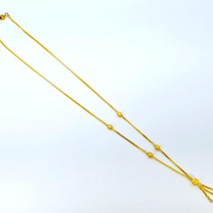 May include: A gold chain necklace with a tassel pendant. The chain has small round beads spaced along its length.