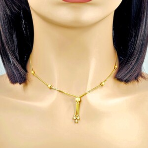 May include: A gold chain necklace with a tassel pendant. The chain has small round beads and the tassel is made of multiple small gold balls.
