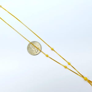 May include: A gold chain necklace with a tassel pendant. The chain is adorned with small round beads.