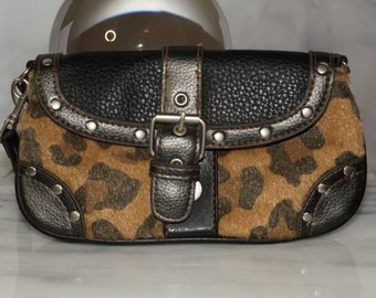 May include: A small black and brown leopard print clutch purse with a silver buckle and metal studs.