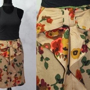 May include: A brown skirt with a floral print and a large bow at the back. The skirt is knee-length and has a fitted silhouette.