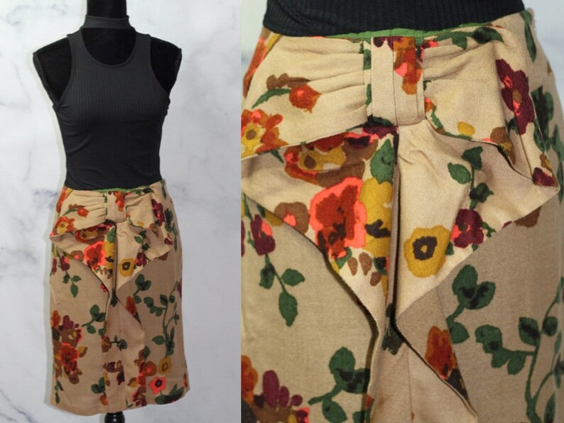 May include: A brown skirt with a floral print and a large bow at the back. The skirt is knee-length and has a fitted silhouette.
