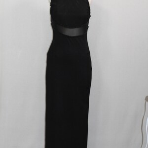 Pode incluir: Um vestido preto maxi sem mangas com um painel transparente na cintura.