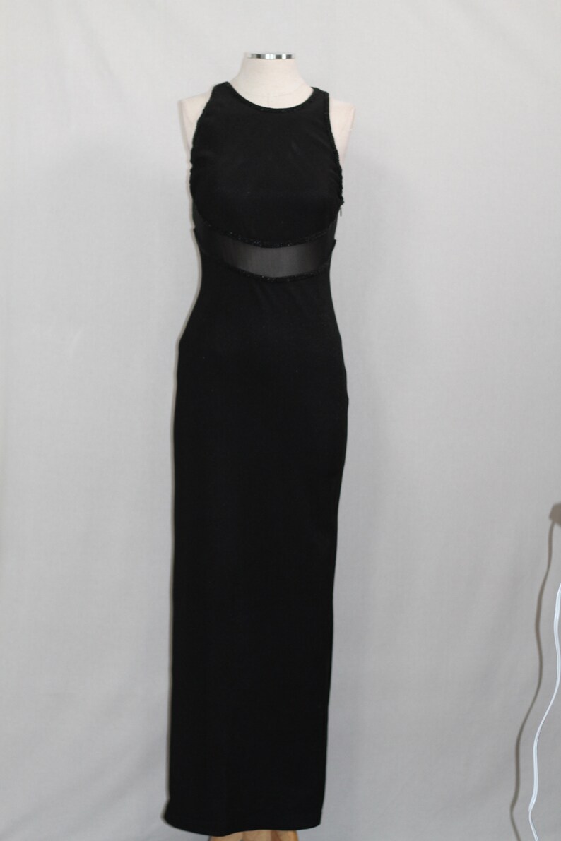 Pode incluir: Um vestido preto maxi sem mangas com um painel transparente na cintura.