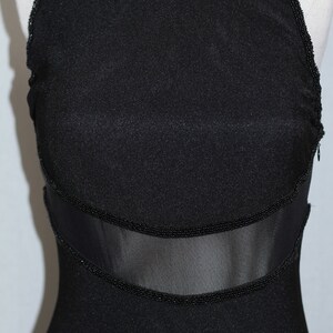 Pode incluir: Um vestido preto sem mangas com um painel de malha e acabamento de contas.
