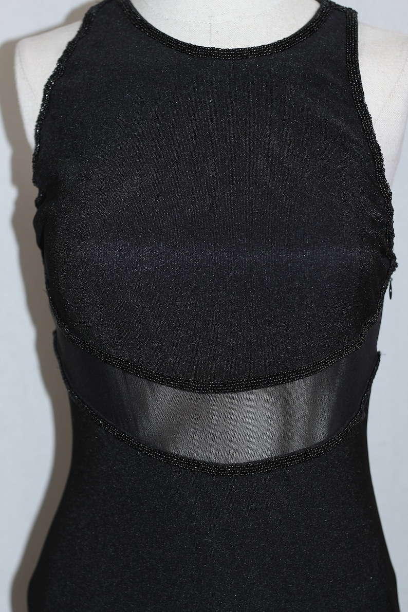 Pode incluir: Um vestido preto sem mangas com um painel de malha e acabamento de contas.