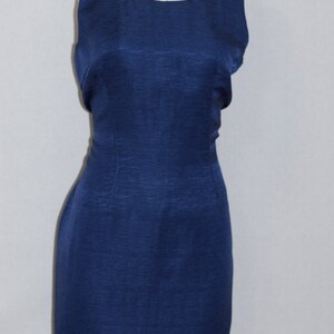 May include: A sleeveless, navy blue dress with a fitted silhouette. The dress has a scoop neckline and a smooth, textured fabric.