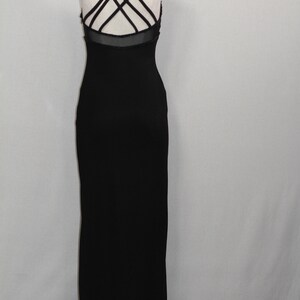Pode incluir: Um vestido maxi preto com um detalhe de tiras cruzadas nas costas. O vestido &eacute; sem mangas e tem uma silhueta ajustada.