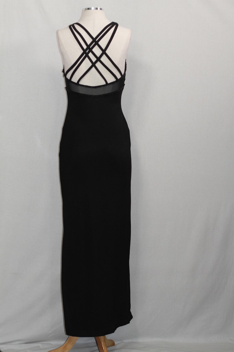 Pode incluir: Um vestido maxi preto com um detalhe de tiras cruzadas nas costas. O vestido &eacute; sem mangas e tem uma silhueta ajustada.