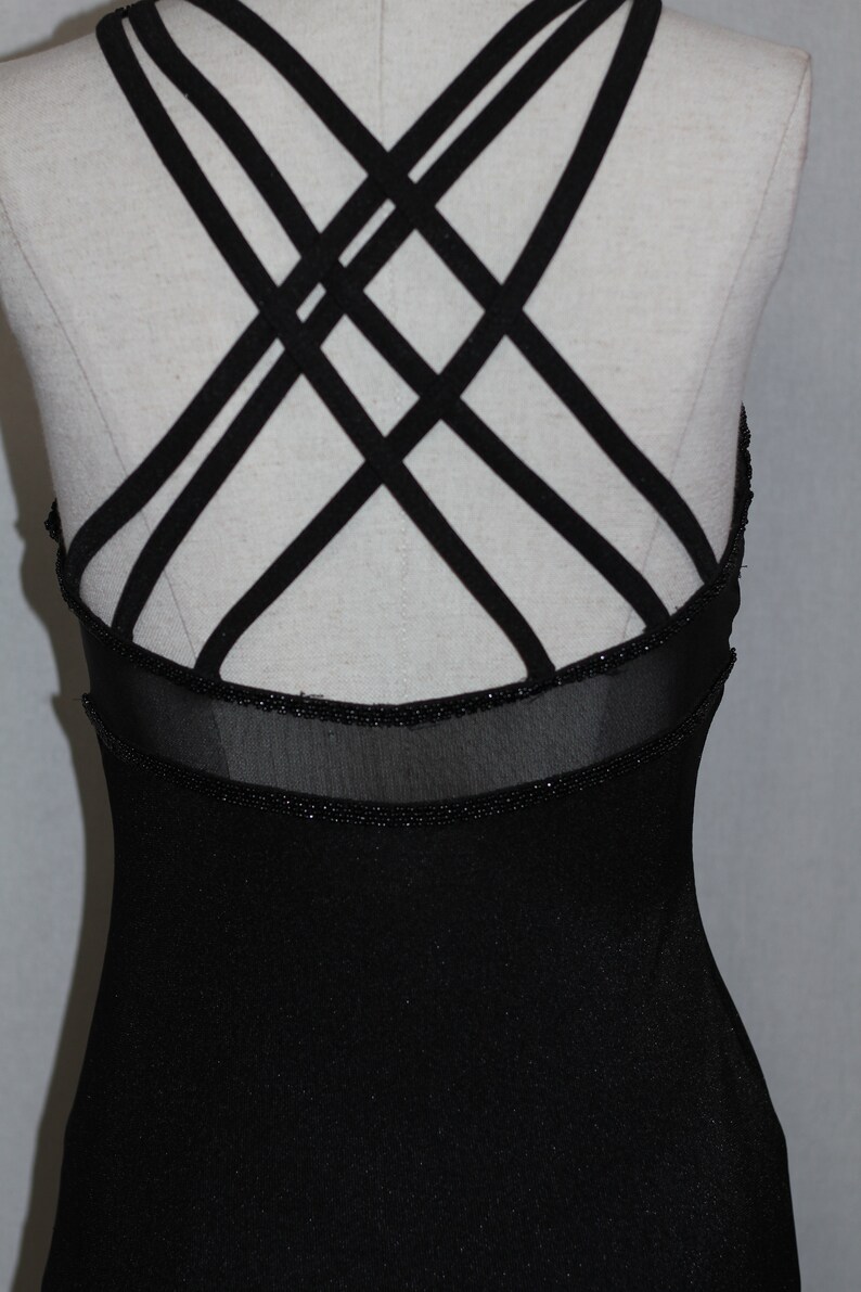 Pode incluir: Vestido preto sem mangas com detalhe nas costas com tiras cruzadas e uma borda de contas.