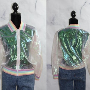 Puede incluir: Chaqueta bomber transparente e iridiscente con cuello, puños y cintura arcoíris. La chaqueta tiene una cremallera frontal y se muestra en un maniquí. El material de la chaqueta refleja tonos verdes y morados.