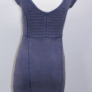 K&ouml;nnte beinhalten: Ein dunkelblaues, kurz&auml;rmeliges Kleid mit V-Ausschnitt und einem plissierten R&uuml;ckenpanel. Das Kleid hat eine figurbetonte Silhouette und einen geraden Saum.