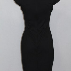 K&ouml;nnte beinhalten: Ein schwarzes &auml;rmelloses Kleid mit einem runden Ausschnitt und einer figurbetonten Silhouette.