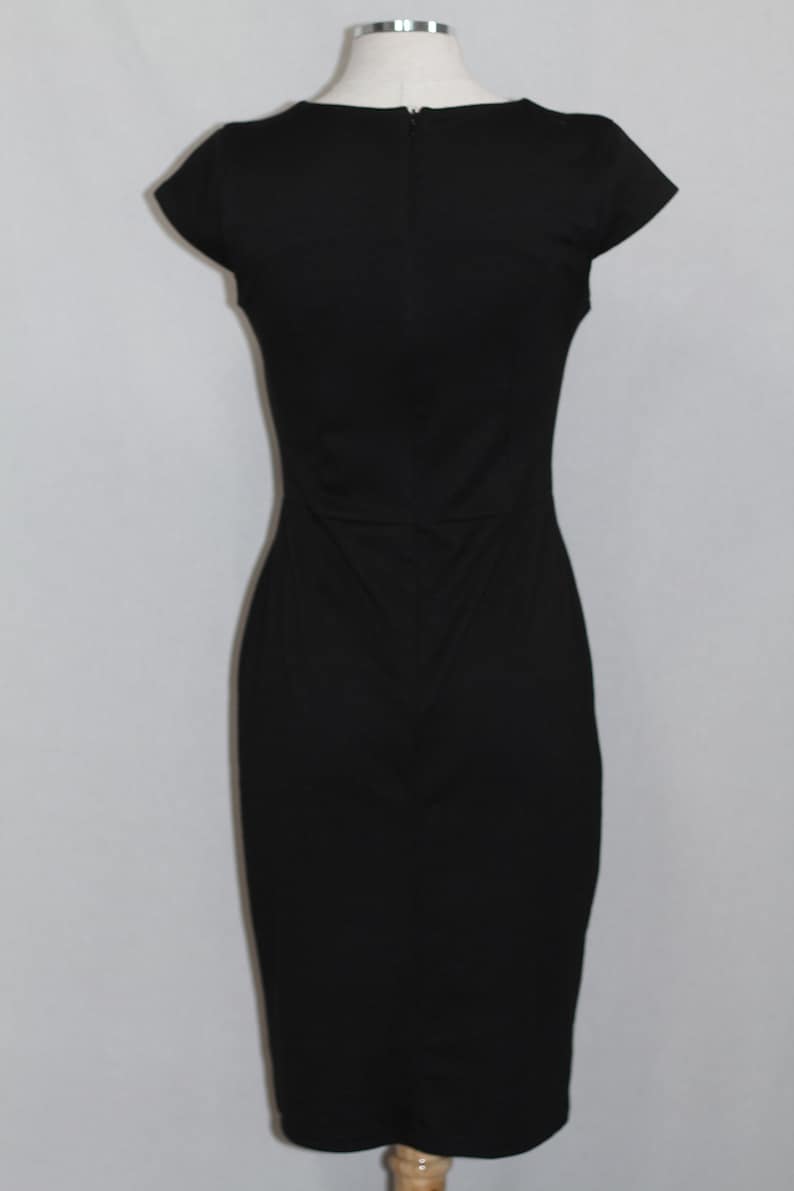 K&ouml;nnte beinhalten: Ein schwarzes &auml;rmelloses Kleid mit einem runden Ausschnitt und einer figurbetonten Silhouette.