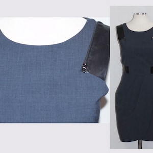 Puede incluir: Un vestido azul oscuro sin mangas con tirantes de cuero negro y un detalle de cremallera. El vestido tiene un corpiño ajustado y una falda ligeramente acampanada.