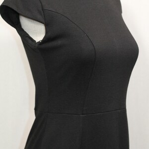 K&ouml;nnte beinhalten: Ein schwarzes &auml;rmelloses Kleid mit Rundhalsausschnitt und figurbetonter Silhouette.