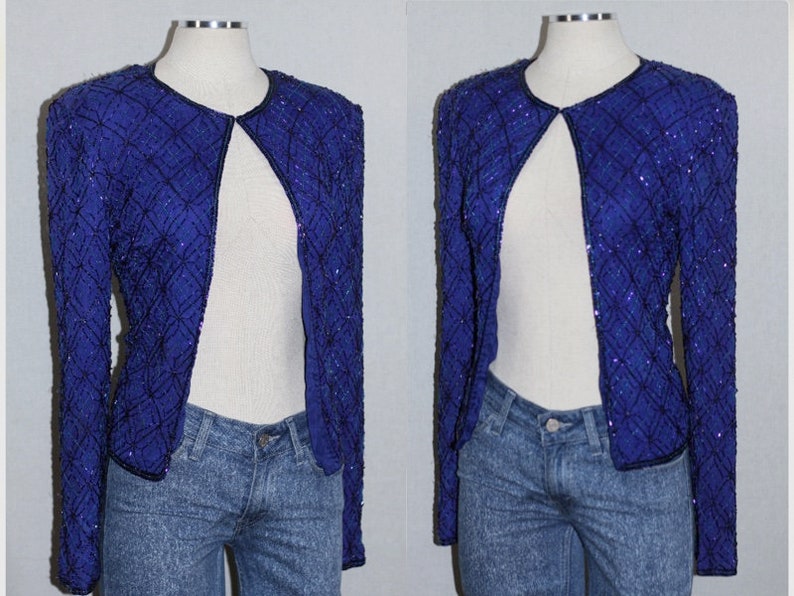 May include: A royal blue sequined jacket with a V-neck and long sleeves. The jacket is open in the front and has a diamond pattern.
