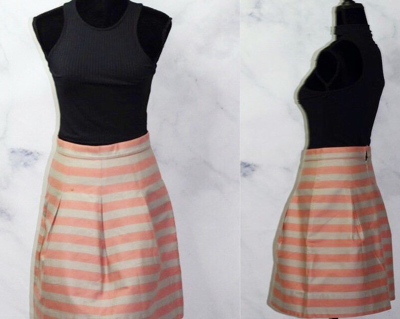 Puede incluir: Una falda de rayas rosa y blancas con un dise&ntilde;o plisado. La falda est&aacute; hecha de una tela sedosa y tiene una cintura ajustada.
