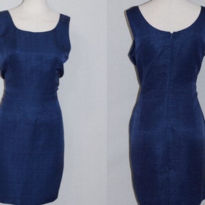 May include: A sleeveless navy blue dress with a fitted silhouette. The dress has a scoop neckline and a back zipper closure.