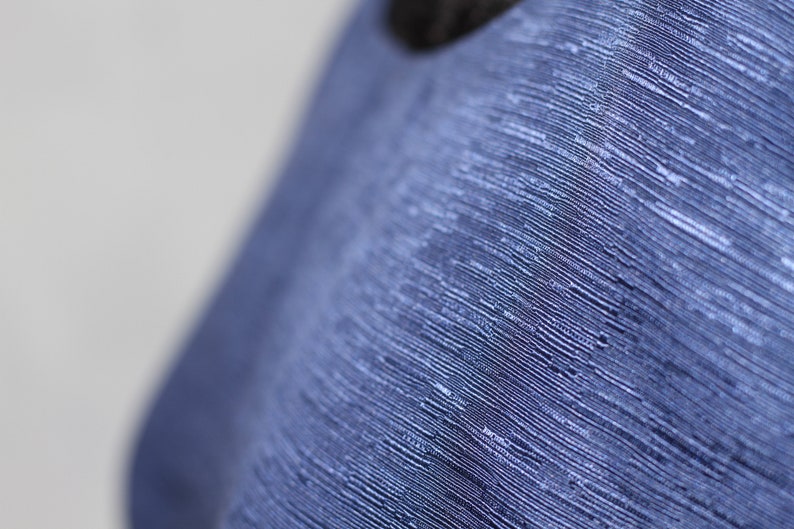 May include: Close-up of a blue fabric with a textured, woven pattern.