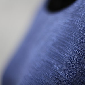 May include: Close-up of a blue textured surface with a smooth, round, black hole in the center.