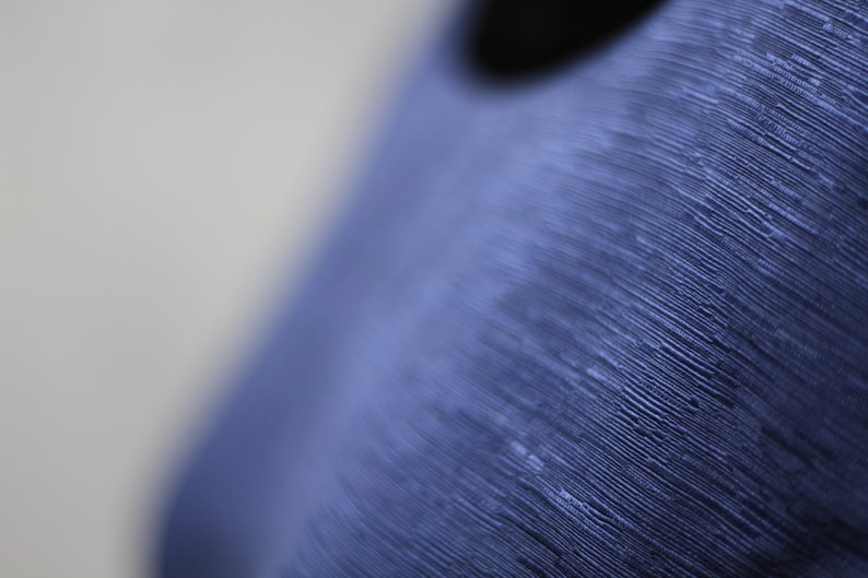 May include: Close-up of a blue textured surface with a smooth, round, black hole in the center.