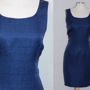 May include: A sleeveless, navy blue dress with a scoop neckline. The dress is made of a textured fabric and has a fitted silhouette.