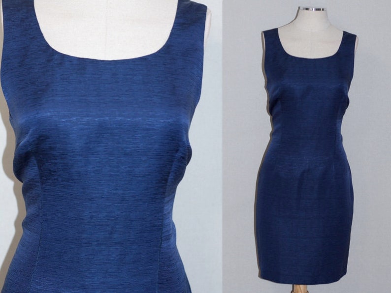 May include: A sleeveless, navy blue dress with a scoop neckline. The dress is made of a textured fabric and has a fitted silhouette.