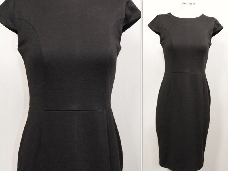 K&ouml;nnte beinhalten: Ein schwarzes Kleid mit kurzen &Auml;rmeln und einer figurbetonten Silhouette. Das Kleid hat einen runden Ausschnitt und ein schlichtes Design.