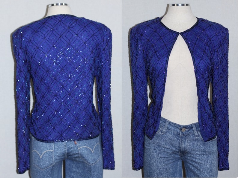 May include: A royal blue sequined jacket with long sleeves and an open front. The jacket is made of a soft, silky fabric and has a delicate, feminine look.