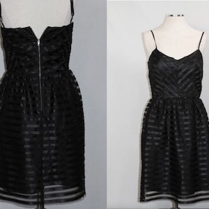 May include: A black sleeveless dress with a striped pattern. The dress has a fitted bodice and a flowing skirt.