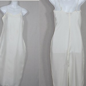 May include: A white slip dress with thin straps. The dress is made of a silky material and has a simple, elegant design.
