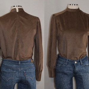 Op de afbeelding: Een bruin, lang mouwig blouse met een hoge mock neck en een rits aan de achterkant. De blouse is gemaakt van een zachte, textuurrijke stof.