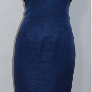 May include: A sleeveless, navy blue dress with a fitted silhouette. The dress is made of a textured fabric and has a simple, elegant design.