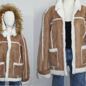 May include: A brown faux fur jacket with a white sherpa lining and a faux fur hood. The jacket has a button closure and two pockets.