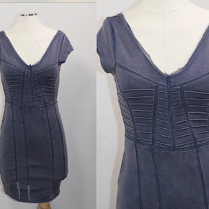 K&ouml;nnte beinhalten: Ein dunkelblaues, kurz&auml;rmeliges Kleid mit einem figurbetonten Oberteil und einem V-Ausschnitt. Das Kleid hat eine strukturierte, leicht abgenutzte Optik.
