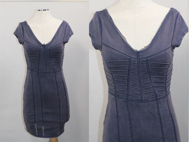 K&ouml;nnte beinhalten: Ein dunkelblaues, kurz&auml;rmeliges Kleid mit einem figurbetonten Oberteil und einem V-Ausschnitt. Das Kleid hat eine strukturierte, leicht abgenutzte Optik.