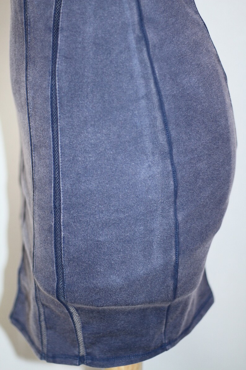 K&ouml;nnte beinhalten: Ein dunkelblaues, figurbetontes Kleid mit einem Mesh-Paneel-Detail an den Seiten. Das Kleid hat einen leicht abgenutzten Look.