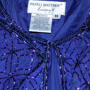 May include: A blue sequined top with a label that reads "PAPELL BOUTIQUE Evening" and "M" for size. The top is made of silk and polyester.