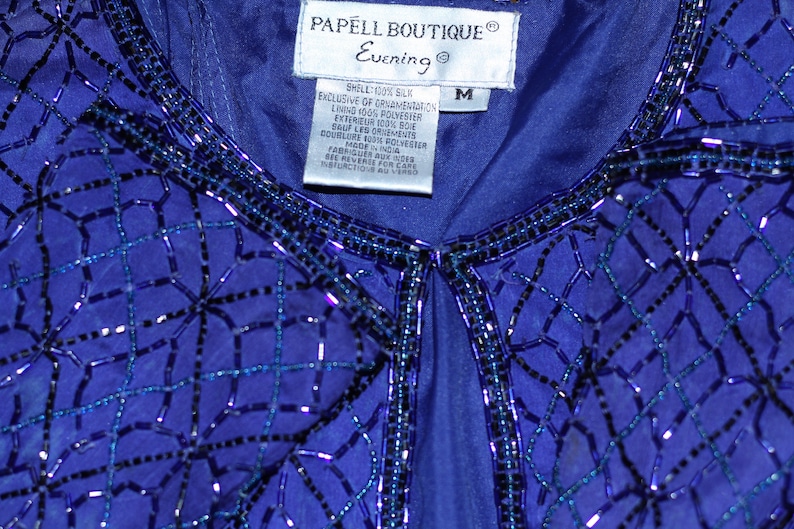 May include: A blue sequined top with a label that reads "PAPELL BOUTIQUE Evening" and "M" for size. The top is made of silk and polyester.