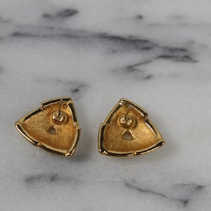 May include: A pair of gold-tone triangle shaped earrings with a textured surface.
