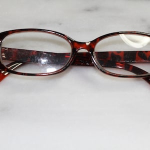 May include: A pair of tortoiseshell eyeglasses with clear lenses.