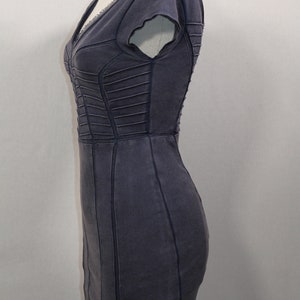K&ouml;nnte beinhalten: Ein dunkelgraues, figurbetontes Kleid mit V-Ausschnitt und kurzen &Auml;rmeln. Das Kleid hat eine strukturierte, leicht abgenutzte Optik und ist mit dekorativen N&auml;hten versehen.