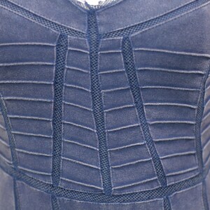 K&ouml;nnte beinhalten: Nahaufnahme eines blauen Jeanskleides mit einem geometrischen Muster aus N&auml;hten und Mesh-Eins&auml;tzen.