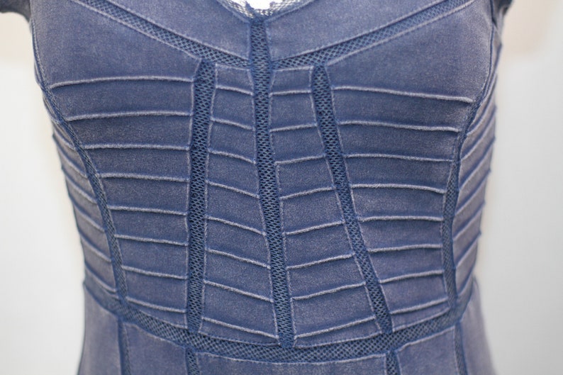 K&ouml;nnte beinhalten: Nahaufnahme eines blauen Jeanskleides mit einem geometrischen Muster aus N&auml;hten und Mesh-Eins&auml;tzen.