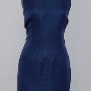May include: A sleeveless, navy blue dress with a square neckline. The dress is made of a textured fabric and has a fitted silhouette.