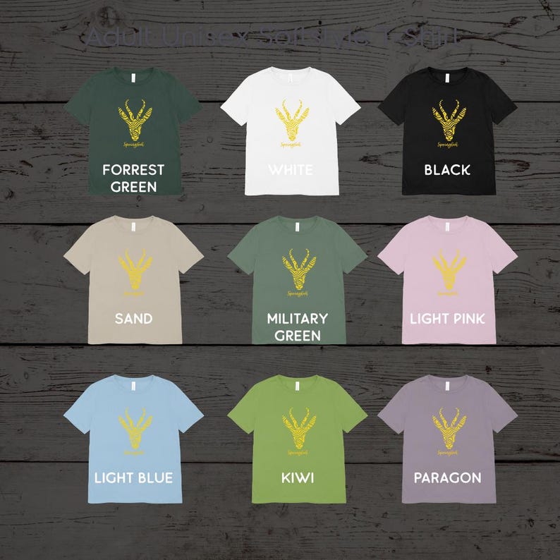 Puede incluir: Se muestran nueve camisetas de diferentes colores, cada una con un dise&ntilde;o dorado de una cabeza de animal estilizada. Las camisetas est&aacute;n disponibles en varios colores, incluyendo verde bosque, blanco, negro, arena, verde militar, rosa claro, azul claro, kiwi y paragon. Cada camiseta tiene la palabra "Springbok" debajo.