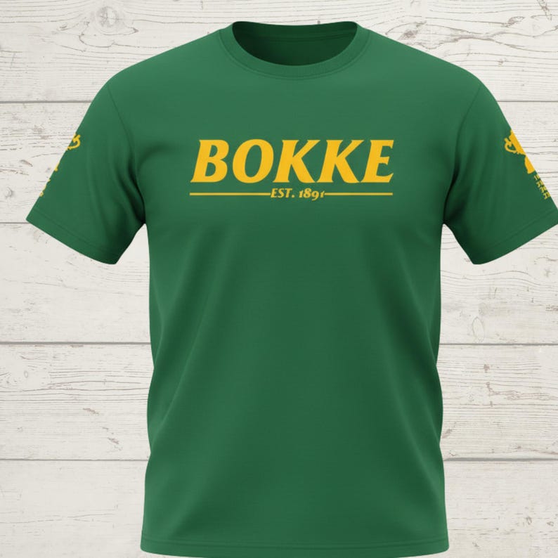 May include: A green t-shirt with the word "BOKKE" in yellow block letters, with "EST. 1891" below. The shirt has short sleeves and a crew neck. The shirt is made of a soft material.