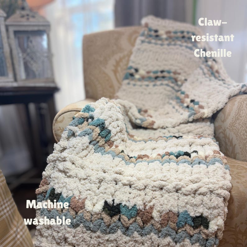 May include: A cream-colored chenille blanket with blue, brown, and black accents is draped over a patterned armchair. The blanket is machine washable and claw-resistant. The text "Claw-resistant Chenille" and "Machine washable" are visible.